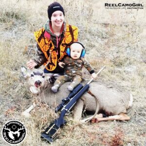Smiling mother posing child with slaughtered deer