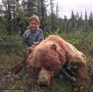 Child posing with slaughtered bear